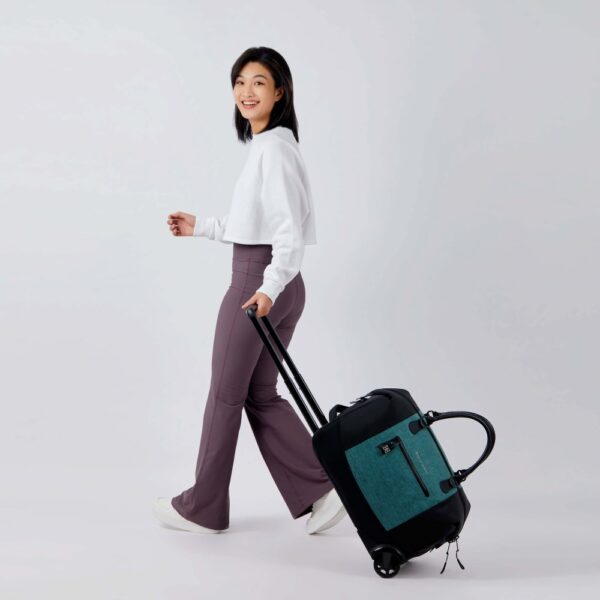 The Trip rolling duffel bag, shown here in teal and black, is made of recycled fabrics and can be carried as a duffel or a roller bag.