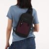 The Sherpani Metro Convertible Travel Sling is shown here in merlot, slung across someone's back. It extends from the right shoulder, across the back, down to the waist.