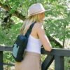 The Sherpani Metro Convertible Travel Sling is shown here in teal, worn across someone's back. This bag is made from 100% recycled materials.
