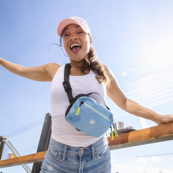 Here's someone wearing the maui blue version of the Hyk Hip Pack as a crossbody bag around their front. They're outside, showing this bag can keep your hands free.