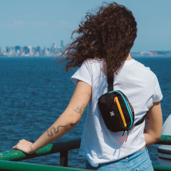 Here's a view from the back. Someone is wearing the Hyk Hip Pack sort of like a backpack. The crossbody strap is across their chest, while the small pack sits on their back. The straps create an L shape from their left shoulder around their right side.