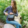 This shows someone wearing the juniper color of the Sadie Crossbody bag. It shows the bag can easily rest on your leg if you're outdoors.