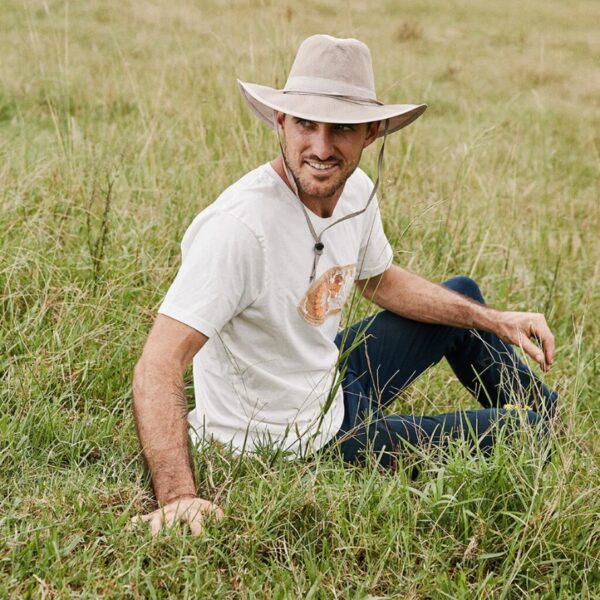 This shows a man wearing the Sunblocker Lightweight Recycled Outdoor Hat. It comes in just one color, sand. It's offered in 5 sizes: small, medium, large, X-Large, XX-Large. It offers 50+ UPF protection and is waterproof. It also has an under-chin strap to keep it in place on windy days.